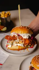 A behind-the-scenes reel showcasing a professional food photography shoot for a burger restaurant. The video alternates between POV shots of the camera setup and high-quality, polished close-ups of the food being styled and plated.
