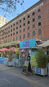 A group of friends visits Pong & Puck in Manchester, showcasing the outdoor terrace, drinks, pizzas, and various competitive socialising games like shuffleboard, table tennis, and skee ball.