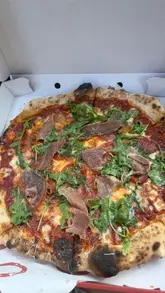 A creator reviews two pizzas from Orto, a pizza venue, while sitting in his car. He describes the toppings, the crust, and the dips, providing an enthusiastic and personal recommendation for the food.
