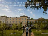 A high-quality, wide-angle shot taken during golden hour, showing a family walking towards a large, historic country house hotel. The composition is balanced and inviting, effectively positioning the venue as an attractive destination for a family getaway.