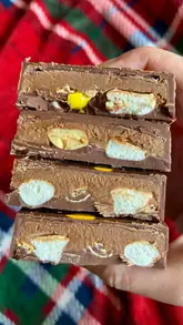 A short, punchy video showcasing two large, filled chocolate bars from the brand Achocco. The video features close-up shots of the bars being broken open to reveal the peanut butter truffle and pistachio kunafa fillings.