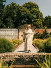 A lifestyle-focused travel shot featuring a creator posing in the gardens of a National Trust property, promoting a day out in the countryside.