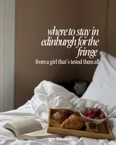 A high-quality, inviting lifestyle image featuring a breakfast tray on a bed, used as a cover for a travel listicle recommending hotels in Edinburgh for the Fringe festival.