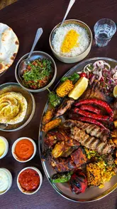 A review of a Middle Eastern 'Mangal Sunday' platter at a restaurant called Roya, featuring a variety of grilled meats, sides, and a pistachio dessert.