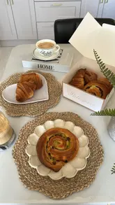 A behind-the-scenes look at a French pastry-making workshop at Comptoir Bakery, showing the process of rolling dough, shaping croissants, and the final baked results.