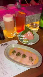 A couple visits Kumori, a trendy handroll sushi bar in Soho, London. The video captures the vibrant atmosphere, the chefs preparing food with a blowtorch, and the couple enjoying various sushi dishes, including toro sashimi, wagyu nigiri, and unique handrolls with soy paper.