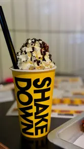 A mother and daughter visit Shake Down, a burger restaurant in Edinburgh, showcasing their meal which includes burgers, loaded fries, chicken tenders, a strawberry waffle, and a cookies and cream milkshake. The video highlights the family-friendly atmosphere and the quality of the food.