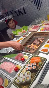 A video review of High Yaki in London's Chinatown, featuring an all-you-can-eat Japanese BBQ experience. The footage includes shots of the restaurant exterior, the interior, various raw meats being grilled at the table, sushi platters, and drinks.