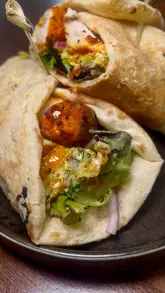 A fast-paced montage showcasing a brunch menu at a restaurant, featuring close-up shots of cocktails, loaded fries, butter chicken sliders, tandoori chicken wraps, and chilli cheese naan bites.