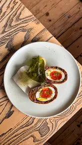 A montage of high-quality food shots and brief interior glimpses of Restaurant Örme in Manchester, highlighting their transition to a sharing-plate menu. The video features close-ups of various dishes including a Scotch egg, beef tartare, lamb, and desserts, set to music with text overlays describing the experience.