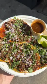 A creator visits a Latin American pop-up restaurant in Bristol, interacting with the owner in the kitchen and sampling their birria tacos and burger. The video highlights the authentic, scratch-made food and the hardworking nature of the family-run business.