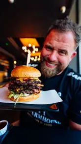 A creator reviews a burger, ribs, chicken wings, and fries at Garrards in Leigh-on-Sea, providing commentary on the taste and quality of the food.