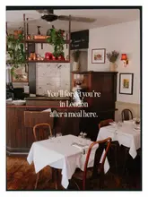 A warm, inviting interior shot of a French bistro in London, featuring neatly set tables with white tablecloths and charming, rustic decor. The image effectively captures the atmosphere of the venue, using warm lighting to create an intimate and authentic Parisian feel.