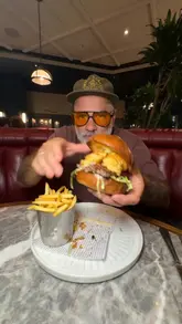 A creator reviews the Burger & Lobster restaurant in Central London, highlighting their new two-course set menu starting at £20. The video features close-ups of various dishes including calamari, beef carpaccio, a smash burger with prawns, and the signature lobster roll, while the creator provides commentary on the value and quality of the food.