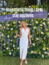 A lifestyle influencer poses in front of a floral backdrop while holding a glass of champagne, with text overlay discussing 'unaesthetic' habits.