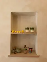 A clean, well-composed, and aesthetically pleasing shot of a shelf display at a cafe, featuring two matcha lattes alongside Japanese-inspired decor and cute figurines.