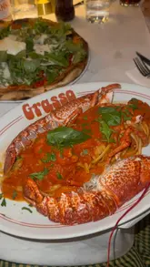 A lively video review of Grasso in London, featuring the creator walking through the venue, sampling various Italian-American dishes like lobster pasta, mozzarella sticks, and desserts, and highlighting the fun atmosphere, including the unique disco toilet.