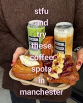 A high-quality, close-up shot of a person holding a cardboard tray featuring two canned iced drinks and two visually appealing pastries. The lighting is soft and natural, effectively highlighting the textures of the food and the branding on the cans. The composition is straightforward and effective for social media, keeping the focus entirely on the products.