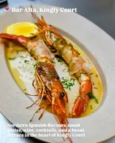 A close-up, overhead shot of two prawns served on a plate with a lemon wedge, presented as a dish from Bar Alta in Kingly Court.