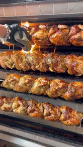 A montage video showcasing the preparation and serving of rotisserie chicken at a venue called Ronda. The video features close-up shots of the rotisserie machine, carving the chicken, assembling a sandwich, and a final spread of the meal including fries, coleslaw, and sauces.