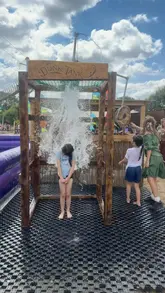 A montage of children enjoying various outdoor activities at Hobbledown Heath, including an inflatable obstacle course, a foam pit, and large climbing structures. The video captures the energetic and playful atmosphere of the venue, focusing on the experience for families.