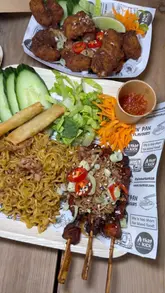 A short, punchy video showcasing various street food dishes including mie goreng, chicken satay, spring rolls, and bao buns. The video focuses on close-up shots of the food to highlight textures and presentation.
