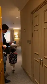 A short, emotive video showing a parent and toddler checking into a hotel room for a staycation, focusing on the emotional reset of travel rather than specific hotel features.