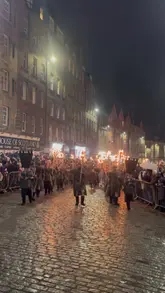 A montage of clips from the Edinburgh Torchlight Procession and Up Helly Aa Viking festival, featuring participants in costume carrying torches, bagpipers, and a burning structure at night.