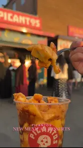 The video promotes new menu items at Picantos, a street food stall located at The Lunar Park. It features close-up shots of a mango dessert (Mangolata) and cheese/chocolate-filled pastry sticks (Tequeños), alongside a brief mention of their existing Birria taco menu. The video uses a fast-paced, vlog-style edit to announce a giveaway promotion for the launch date.