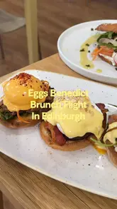 A short video review of Loudons cafe in Edinburgh, highlighting their brunch menu, specifically the 'Eggs Benedict Flight' and smoked salmon bagel, alongside coffee and fresh orange juice.