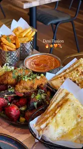 A promotional video for Desi Fusion in Aldridge, featuring a variety of Indian street food dishes, including a mixed grill platter, curries, and naan, alongside shots of the restaurant's interior and exterior.
