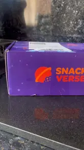 An unboxing video of a 'SnackVerse' subscription box featuring snacks from Spain, including Doritos pizza pepperoni bits and fried egg crisps.