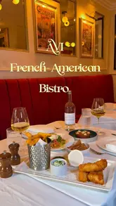A montage-style video showcasing the interior and various dishes at AVI Bistrot Americain in Belgravia. The video features close-up shots of food preparation and presentation, including shrimp, burrata, tartare, and dessert, set to music with text overlays describing the restaurant's concept.