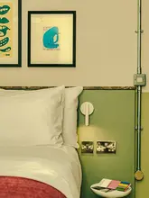 A stylish, well-composed interior shot of a boutique hotel room, highlighting the decor, lighting, and bedside details.