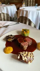 A cinematic montage showcasing a fine dining experience at a British manor house, featuring close-ups of sophisticated plated dishes and the elegant interior and garden surroundings.