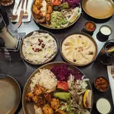 A flat-lay photograph of a Turkish meal spread, including chicken shish, rice, salad, hummus, and patlıcan ezme, taken from an overhead perspective at a restaurant.