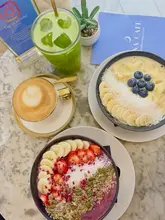 A bright, overhead flat-lay shot of a healthy brunch spread at Luna Cafe, featuring two vibrant smoothie bowls, a green juice, and a latte arranged on a marble table.