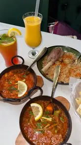 A promotional reel for a new Indian restaurant in Huddersfield, featuring close-up shots of various curries, rice dishes, naan, drinks, and desserts, alongside glimpses of the restaurant's floral-decorated interior.