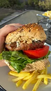 A short, handheld video demonstrating the preparation of Yeo Valley beef and lamb burgers on a home BBQ, featuring the cooking process and assembly of the final burger.