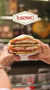 A high-quality, rhythmic montage showcasing the preparation and final presentation of Italian-style sandwiches at Toscano in Edinburgh, featuring close-ups of ingredients and the menu.