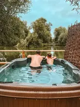 A lifestyle shot featuring a father and son in a hot tub overlooking a lake at Fairwood Lakes, promoting a luxury staycation experience.
