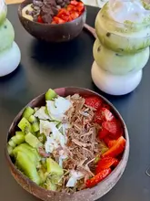 A top-down shot of two acai bowls and two layered iced matcha drinks on a black table. The image captures the vibrant colours of the fruit and the aesthetic presentation of the drinks, typical of a trendy cafe setting.