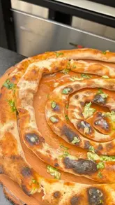 A short, instructional video demonstrating how to make a garlic bread swirl stick using a home pizza oven.
