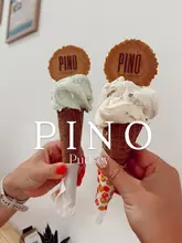 A close-up, eye-level shot of two hands holding gelato cones from a local venue, with the brand name and location overlaid on the image.
