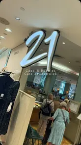 A montage of food and drink items at Cafe 21 in Fenwick, featuring close-ups of cakes, a profiterole with chocolate sauce, coffee, and champagne.