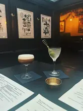 A clean, atmospheric shot of two cocktails placed on a table at The Golden Pineapple in Brighton, highlighting the venue's moody interior and drink presentation.