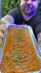 A food review of Asha in Brierfield, where the creator samples a mixed kebab, king prawn saag, keema rice, and garlic naan, providing commentary on the flavors and quality.