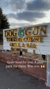 A static, clear shot of the exterior signage for 'Dog & Gun Turkish Cuisine Grill & Bar', accompanied by text overlay highlighting the venue's family-friendly amenities.