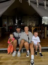 A family portrait taken on the deck of a glamping tent at a farm stay in Wales, capturing a relaxed, outdoor family holiday vibe.