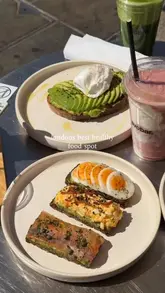 A bright, overhead shot of a brunch spread at The Avo Bar, featuring avocado toast with various toppings and smoothies.